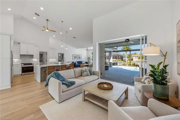 Living area featuring ceiling fan, lofted ceiling, light wood finished floors, and hanging lights