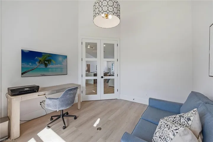 Office area with french doors, a high ceiling, and light wood-style flooring