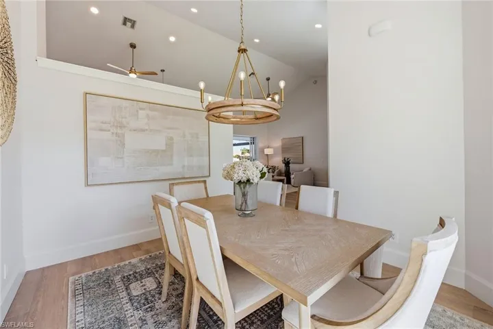 Dining area with light wood-style floors, lofted ceiling, a ceiling fan, and hanging lights