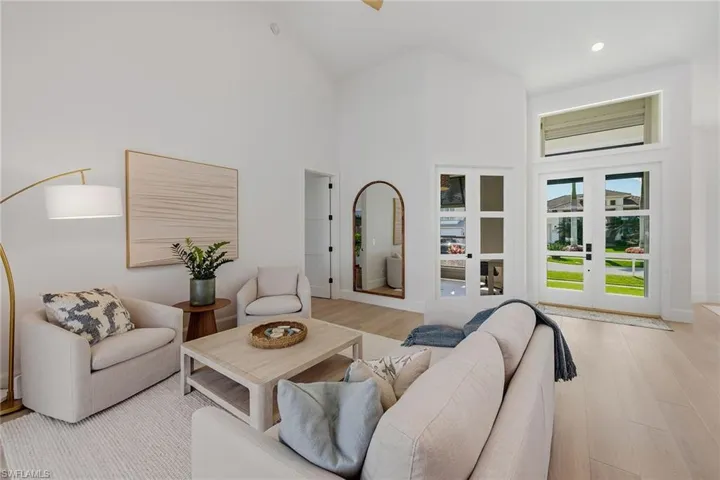 Living area with french doors, a high ceiling, light wood-type flooring, a ceiling fan, and recessed lighting