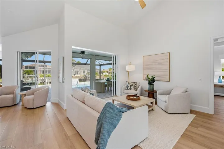 Living room with a sunroom, a ceiling fan, vaulted ceiling, and light wood-type flooring