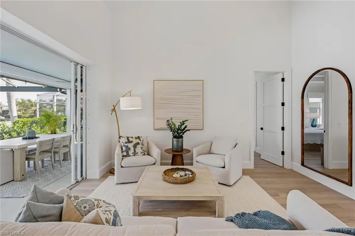 Living area featuring light wood-style floors, a high ceiling, and a sunroom