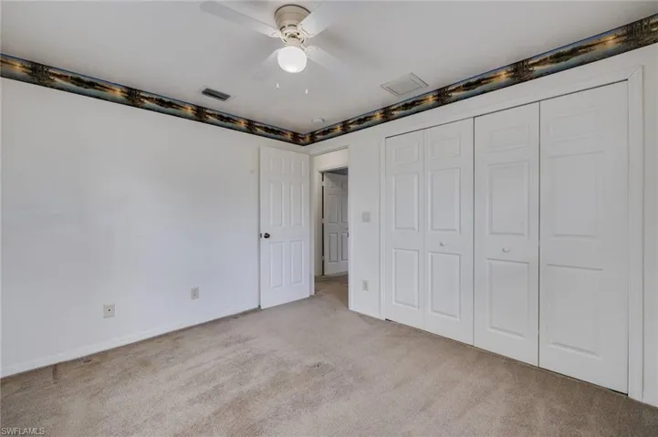 Unfurnished bedroom with light carpet, a closet, and a ceiling fan