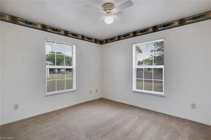 Spare room featuring ceiling fan, healthy amount of natural light, and light colored carpet