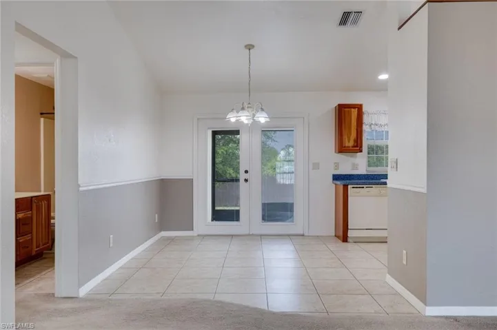 Unfurnished dining area featuring light tile patterned floors, a chandelier, and french doors