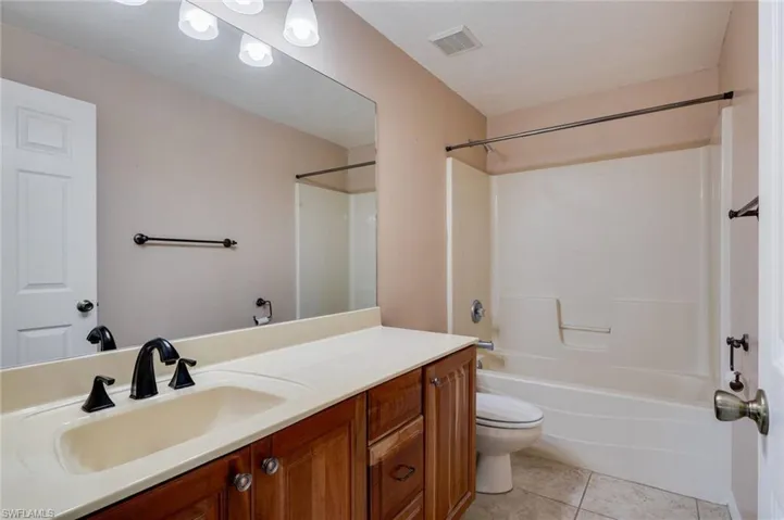Bathroom with vanity, light tile patterned floors, and shower / tub combination