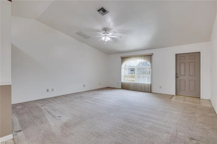 Spare room featuring light colored carpet, a ceiling fan, radiator heating unit, and vaulted ceiling