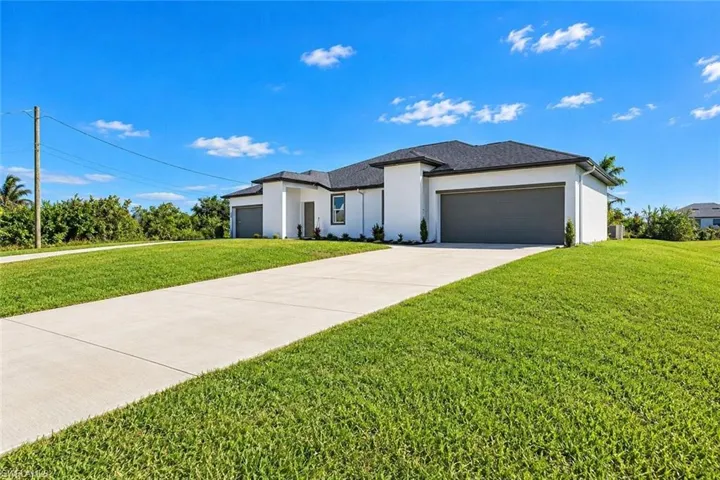 Single-story residence featuring a smooth stucco exterior, multi-car garage, concrete driveway, and a shingled roof, set upon a grass lawn