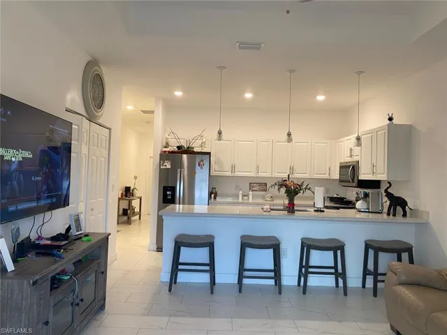 Kitchen featuring visible vents, pendant lighting, a peninsula, white cabinets, and stainless steel appliances