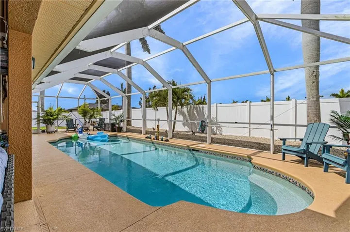 View of swimming pool featuring glass enclosure, a sunroom, a fenced backyard, and patio surround