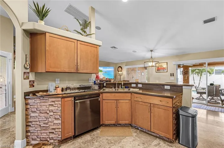 Kitchen with dishwasher, a peninsula, a chandelier, and wood finish cabinets