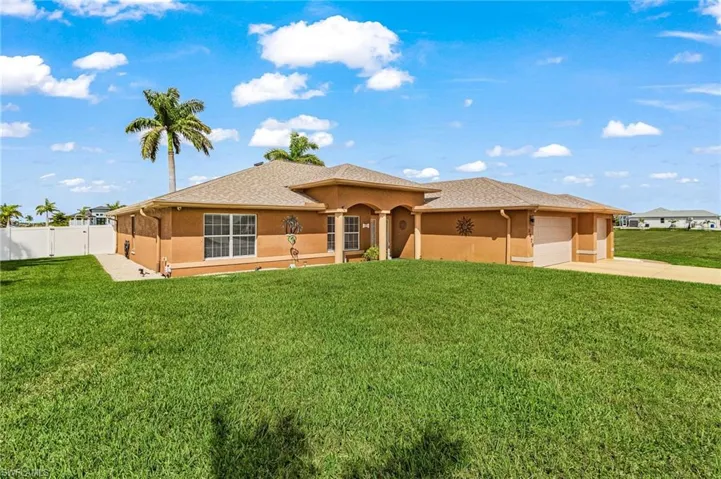 View of front of house with stucco siding, a front lawn, a garage, driveway, and roof with shingles