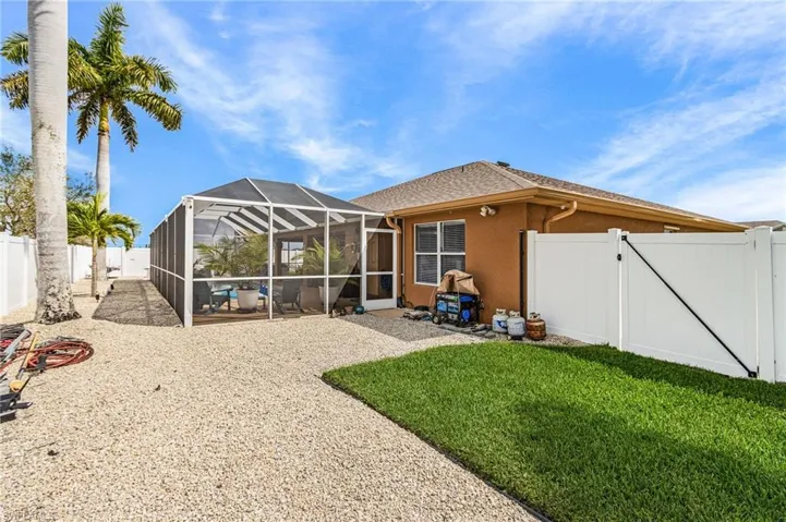Back of property with a gate, a fenced backyard, glass enclosure, stucco siding, and a patio area