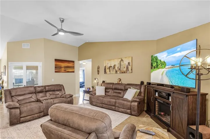 Living room featuring ceiling fan, lofted ceiling, and a fireplace