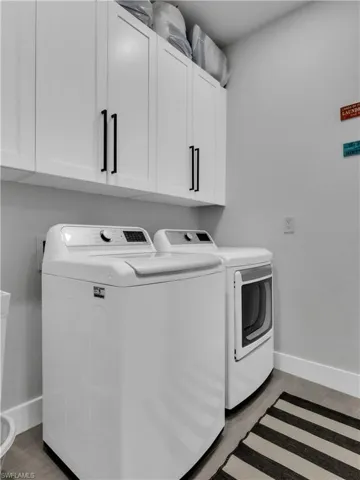 Utility space featuring white cabinetry with black hardware, wood-finish flooring, and light gray walls