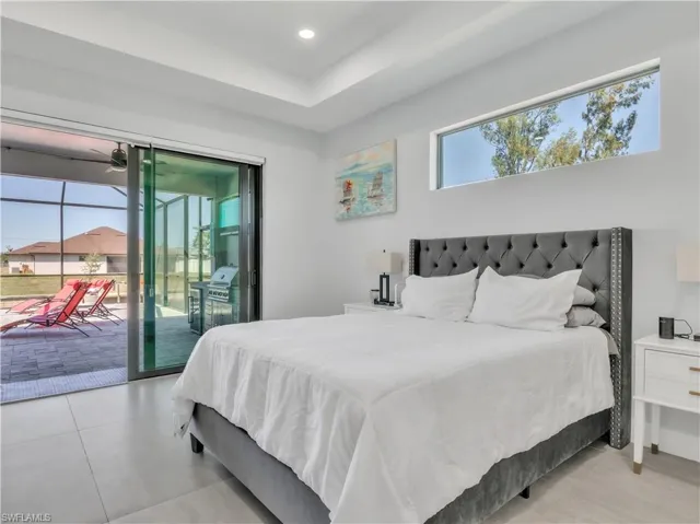 Tray ceiling with recessed lighting, large format tile flooring, and sliding glass doors opening to a screened patio