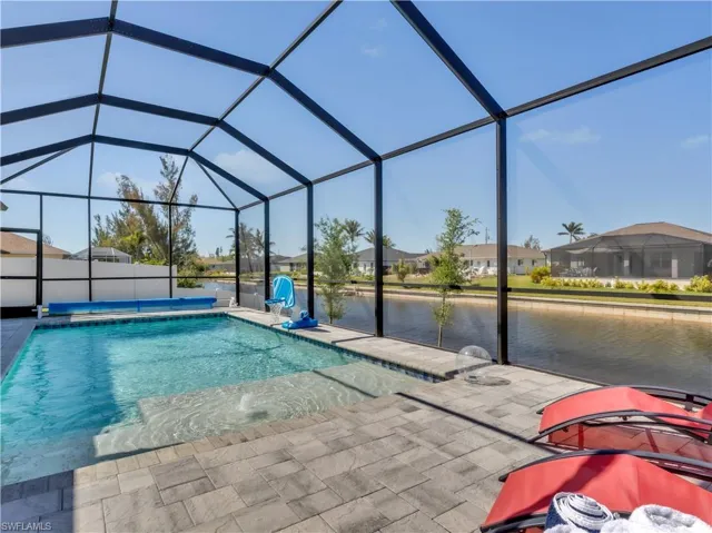 Screened pool enclosure with a paved deck, built-in water feature, and direct canal access