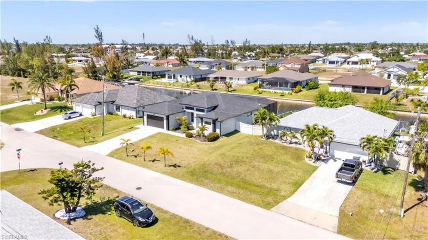 Single-story residence featuring a gray shingle roof, concrete driveway, and a white fence