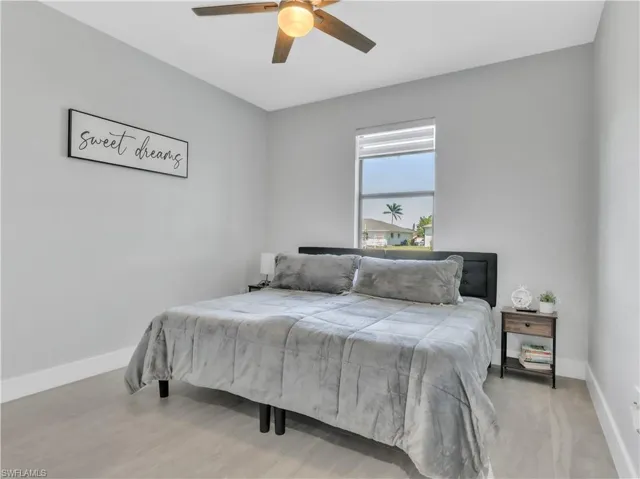 Neutral-toned room with wood-finish flooring, a ceiling fan with integrated lighting, and a single window with blinds