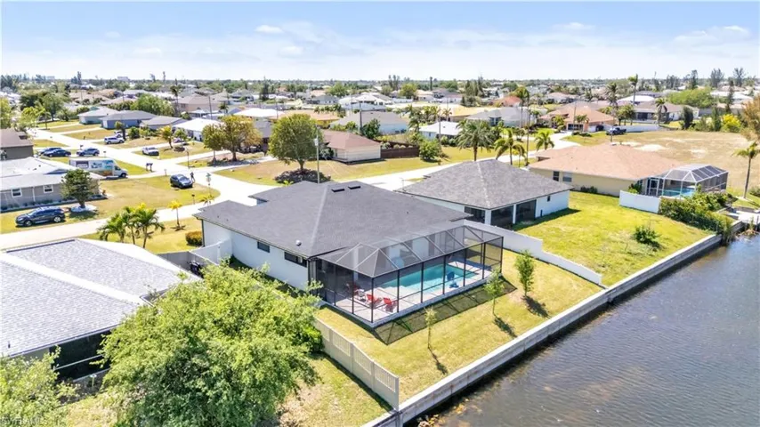 Screened-in pool with a water-front location, featuring a concrete retaining wall, a dedicated dock, and a spacious grassy yard
