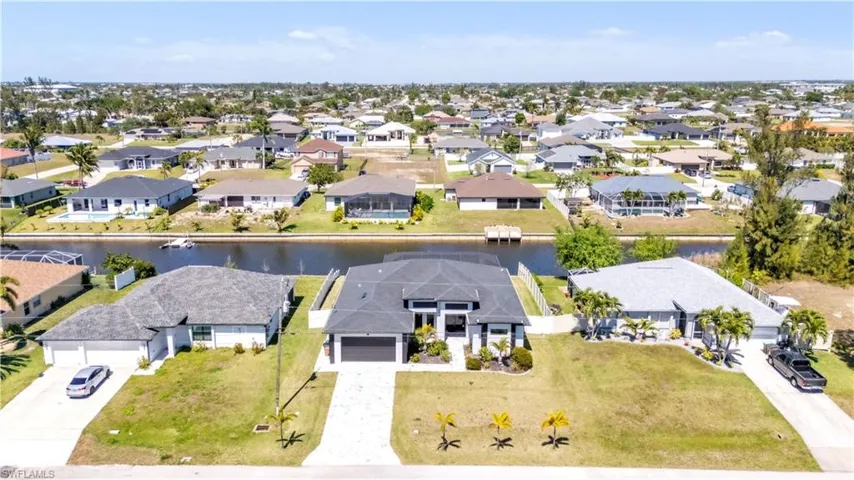 Modern single-story residence featuring a dark tile roof, paved driveway, and established landscaping