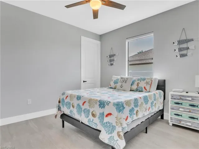 Bedroom featuring light gray walls, wood-finish flooring, a contemporary ceiling fan with integrated lighting, and a single window offering natural light