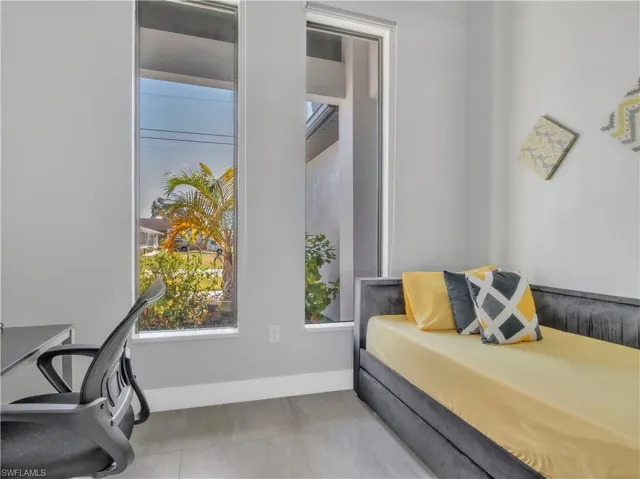 Room featuring two tall vertical windows, light gray walls, and gray tile flooring