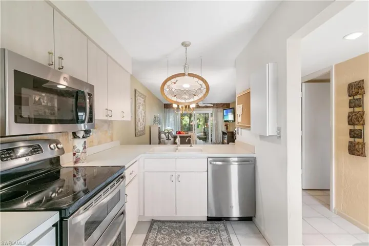 Kitchen featuring appliances with stainless steel finishes, light tile flooring, hanging light fixtures, sink, and a chandelier