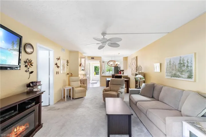 Carpeted living room with ceiling fan with notable chandelier