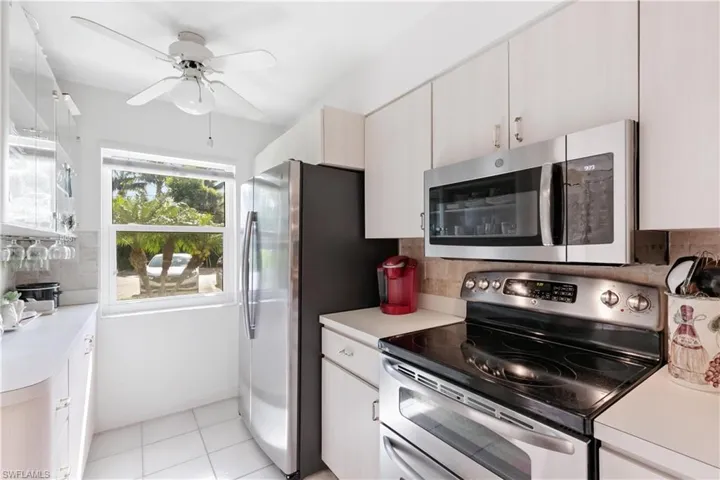 Kitchen with ceiling fan, stainless steel appliances, light tile flooring, and tasteful backsplash