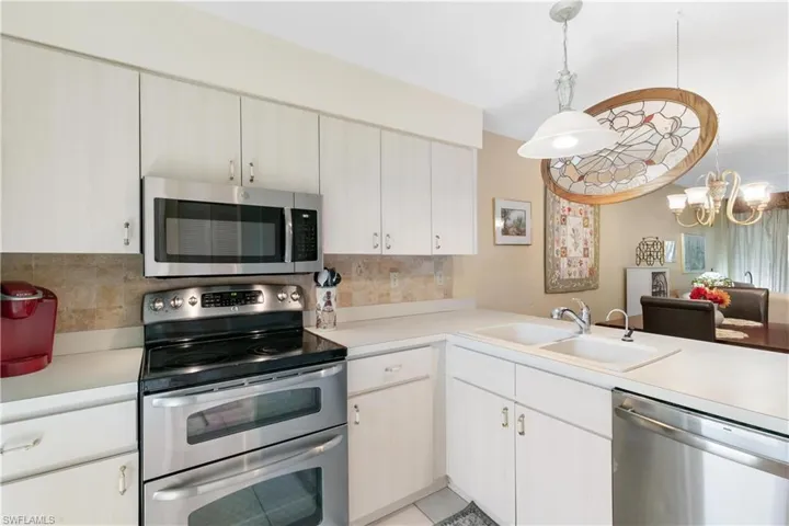 Kitchen featuring sink, hanging light fixtures, backsplash, and stainless steel appliances