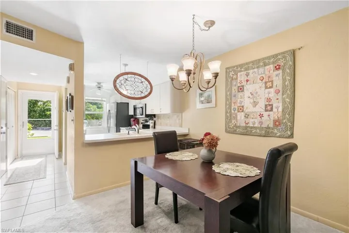 Carpeted dining space with ceiling fan with notable chandelier