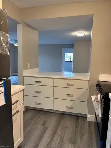 Kitchen storage featuring white cabinets and light countertops with wood finished floors