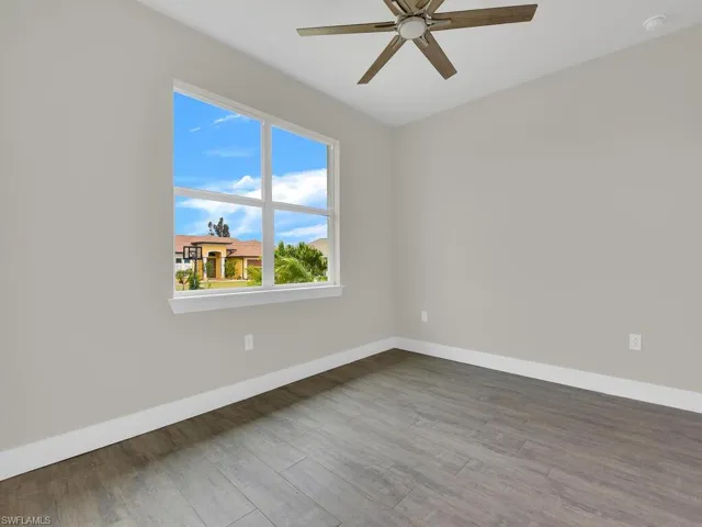 Spare room featuring a ceiling fan, baseboards, and wood finished floors