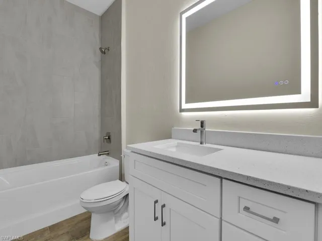 Full bathroom with shower / bath combination, vanity, toilet, and wood finished floors