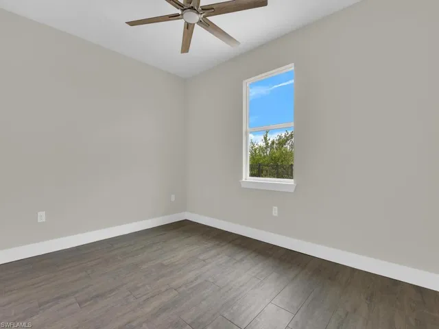 Unfurnished room with baseboards, ceiling fan, and wood finished floors