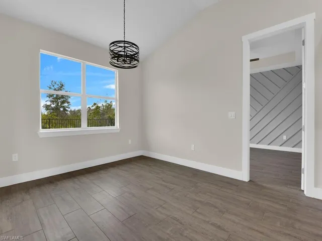 Unfurnished dining area featuring baseboards, wood finished floors, a chandelier, and vaulted ceiling