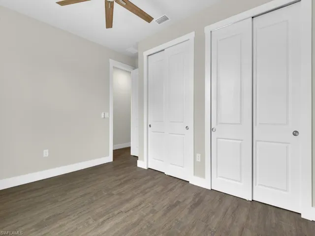 Unfurnished bedroom with visible vents, wood finished floors, two closets, baseboards, and ceiling fan