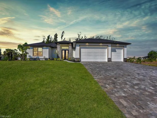 Prairie-style home with french doors, a garage, a lawn, stucco siding, and decorative driveway