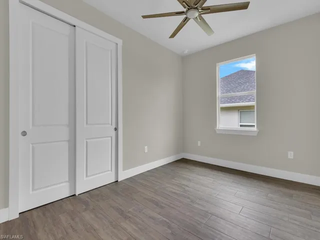 Unfurnished bedroom with baseboards, ceiling fan, and wood finished floors