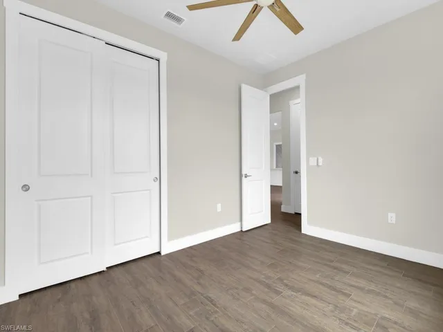 Unfurnished bedroom with baseboards, visible vents, wood finished floors, and a closet