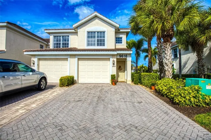 View of front of house with decorative driveway, a tiled roof, stucco siding, and an attached garage
