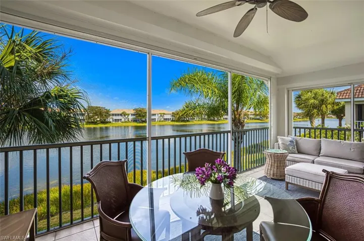 Sunroom / solarium with a water view, vaulted ceiling, and tile patterned floors