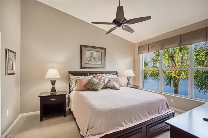 Bedroom with lofted ceiling, light carpet, and a ceiling fan