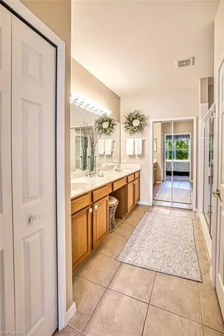 Full bathroom featuring double vanity, a closet, a shower stall, and light tile patterned floors