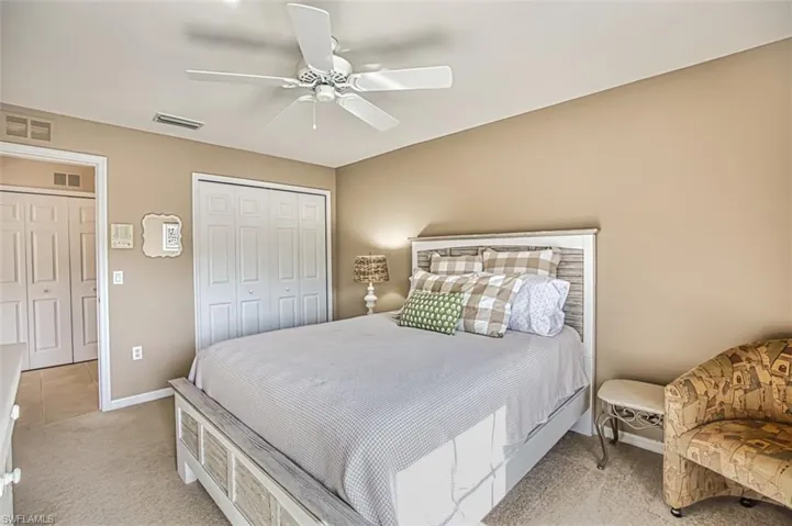 Bedroom with ceiling fan, light colored carpet, and a closet