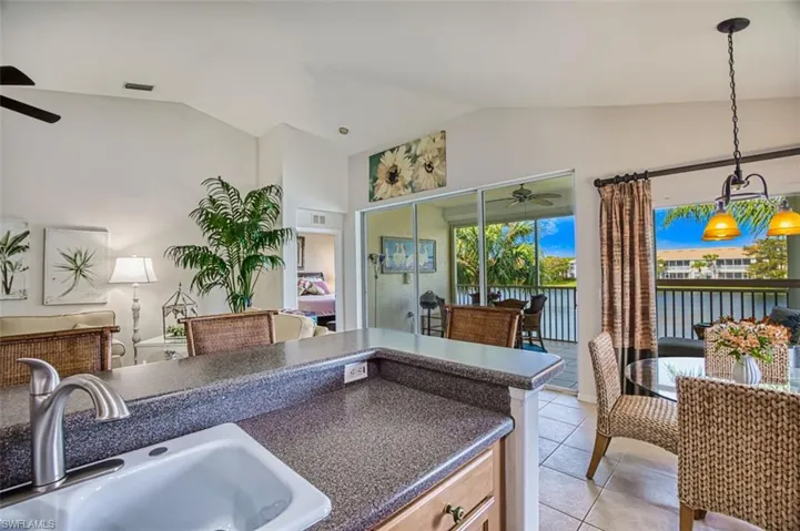 Kitchen featuring ceiling fan, lofted ceiling, hanging light fixtures, a water view, and light tile patterned floors