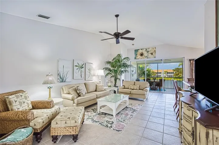 Living room with light tile patterned floors, a ceiling fan, and high vaulted ceiling