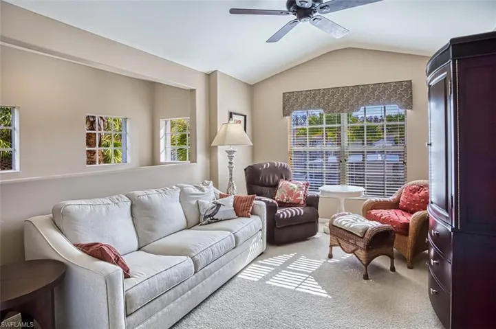 Living room featuring vaulted ceiling, a ceiling fan, and carpet flooring