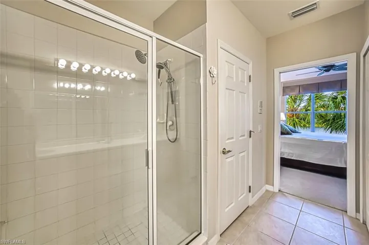 Ensuite bathroom featuring a shower stall and light tile patterned flooring